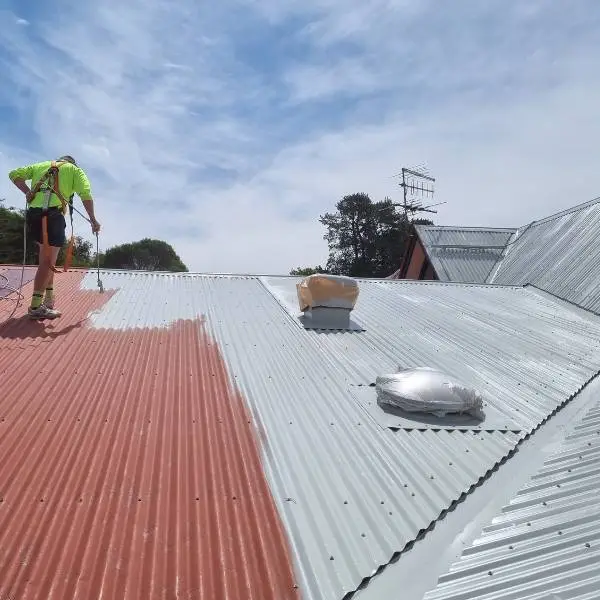 Our roofer spray-applying a membrane top coat during a metal roof restoration