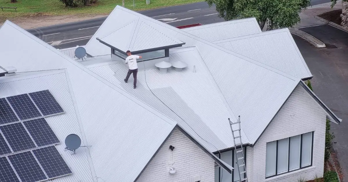 Completed metal roof restoration — freshly recoated roof with our roofer on site