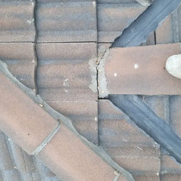 Cracked ridge capping bedding found during an on-roof inspection β the kind of fault we photograph and report